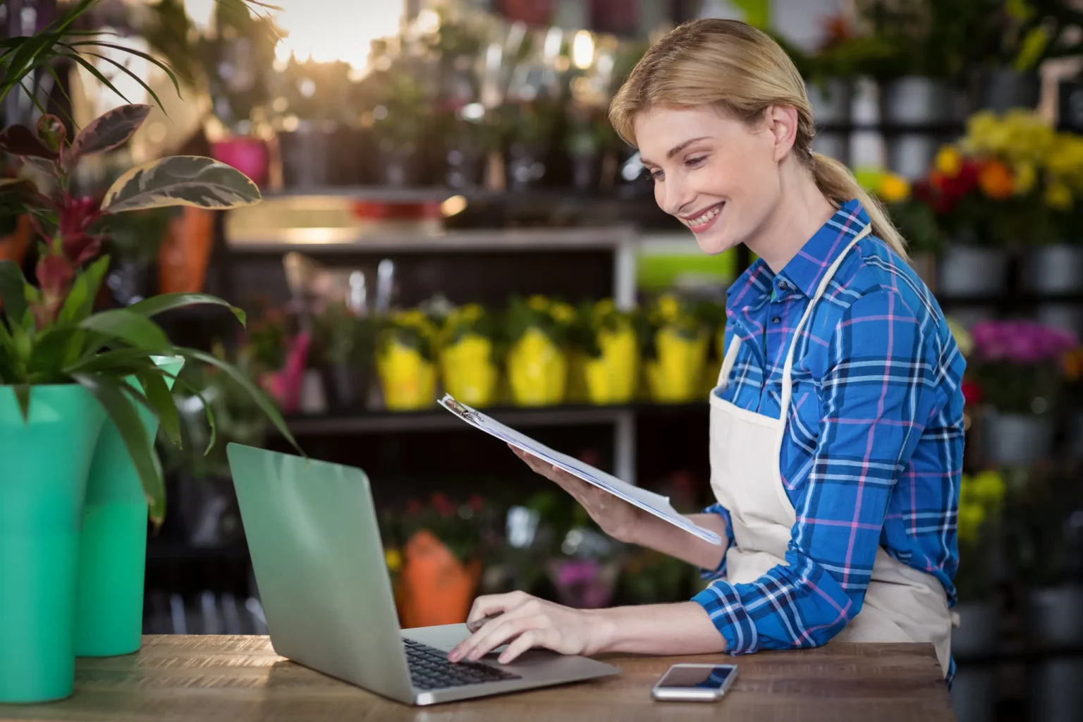 A florist checking orders on a laptop in her shop