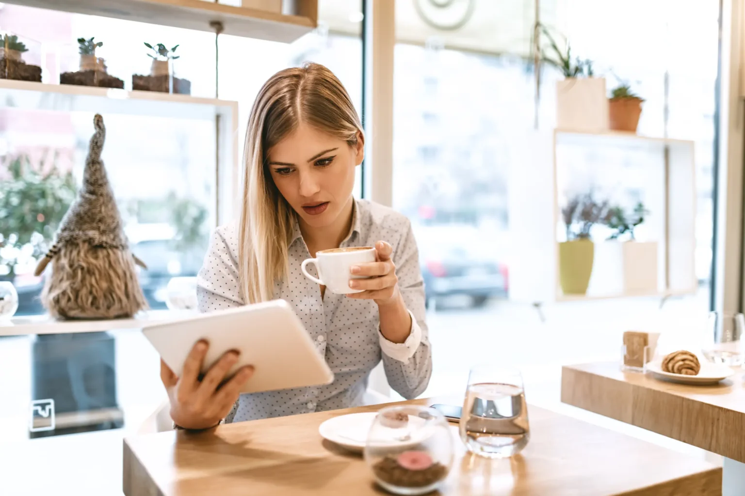 A woman reading on a tablet over coffee in a café